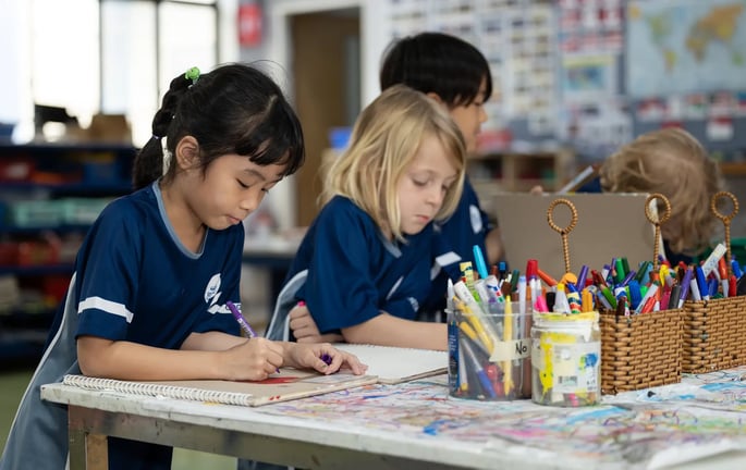 Children drawing with markers during a classroom art activity.
