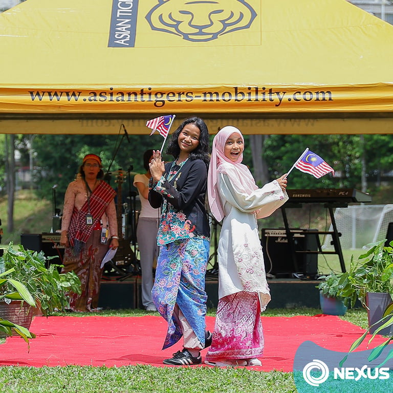 Students celebrate Malaysian culture with music, traditional dress, and a joyful display of national pride during a school event.