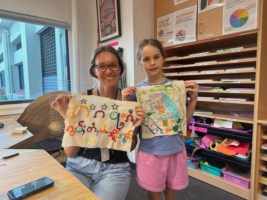 Parent and child showing artwork from an embroidery program.