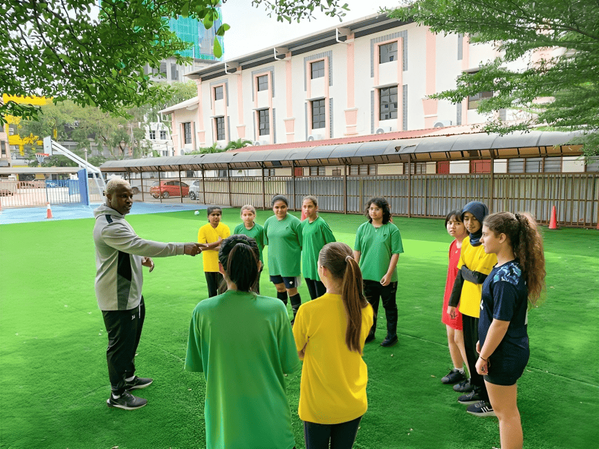 The girls’ football team training with coach Jerome on campus turf.