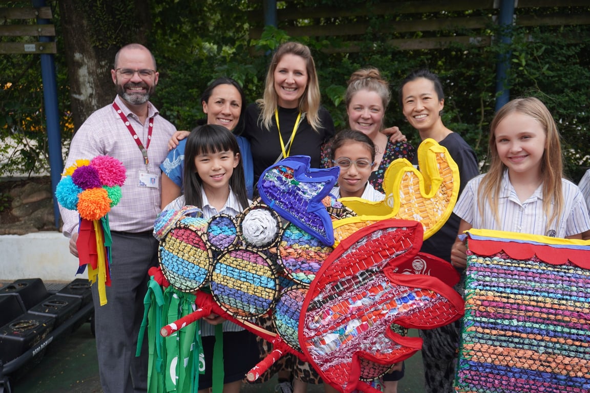 Students and staff presenting a dragon sculpture made from recycled materials.