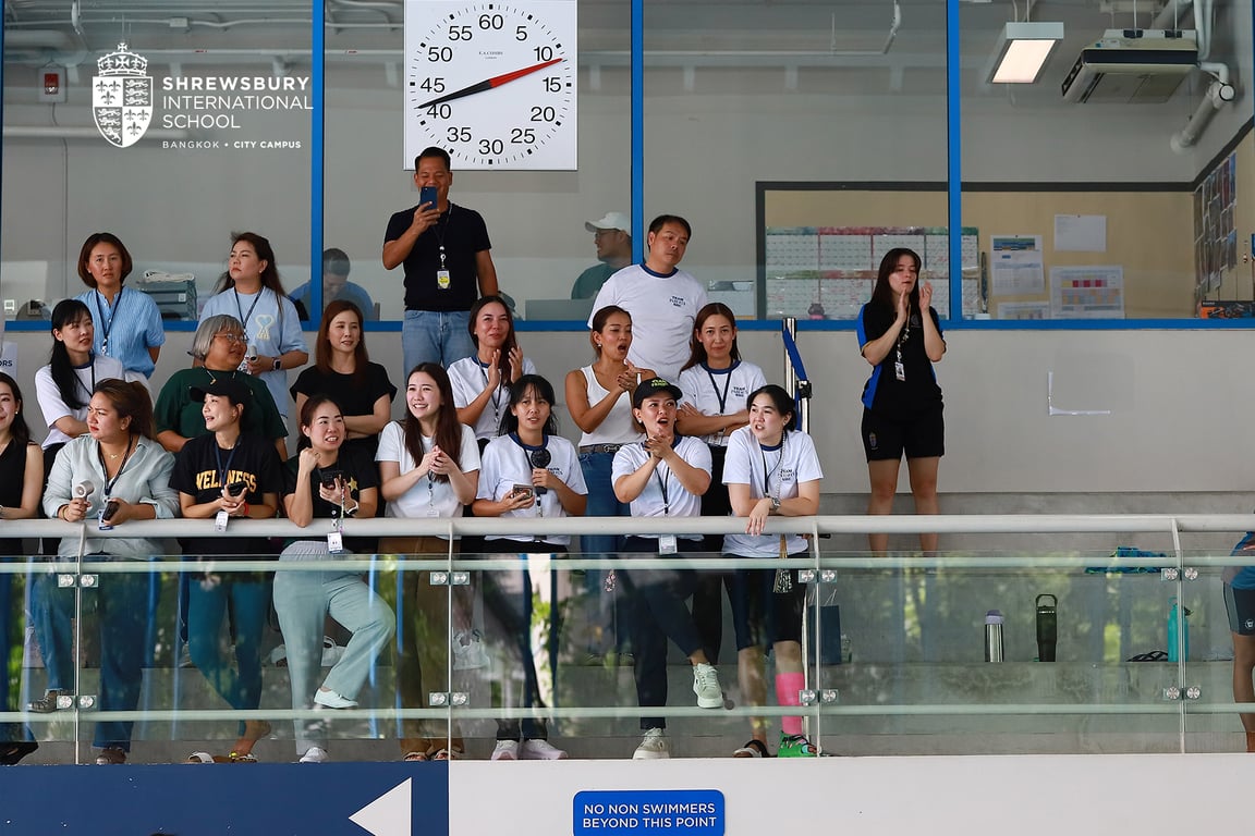 Families cheering for their kids at a swimming session.