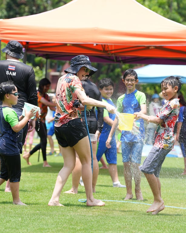 Students and teachers cooling off with fun splashes during Songkran celebrations.