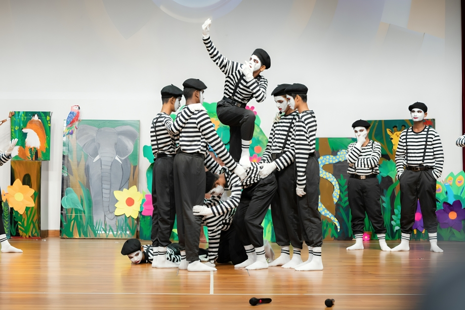 Students perform a mime act during a school stage production with creative set design.