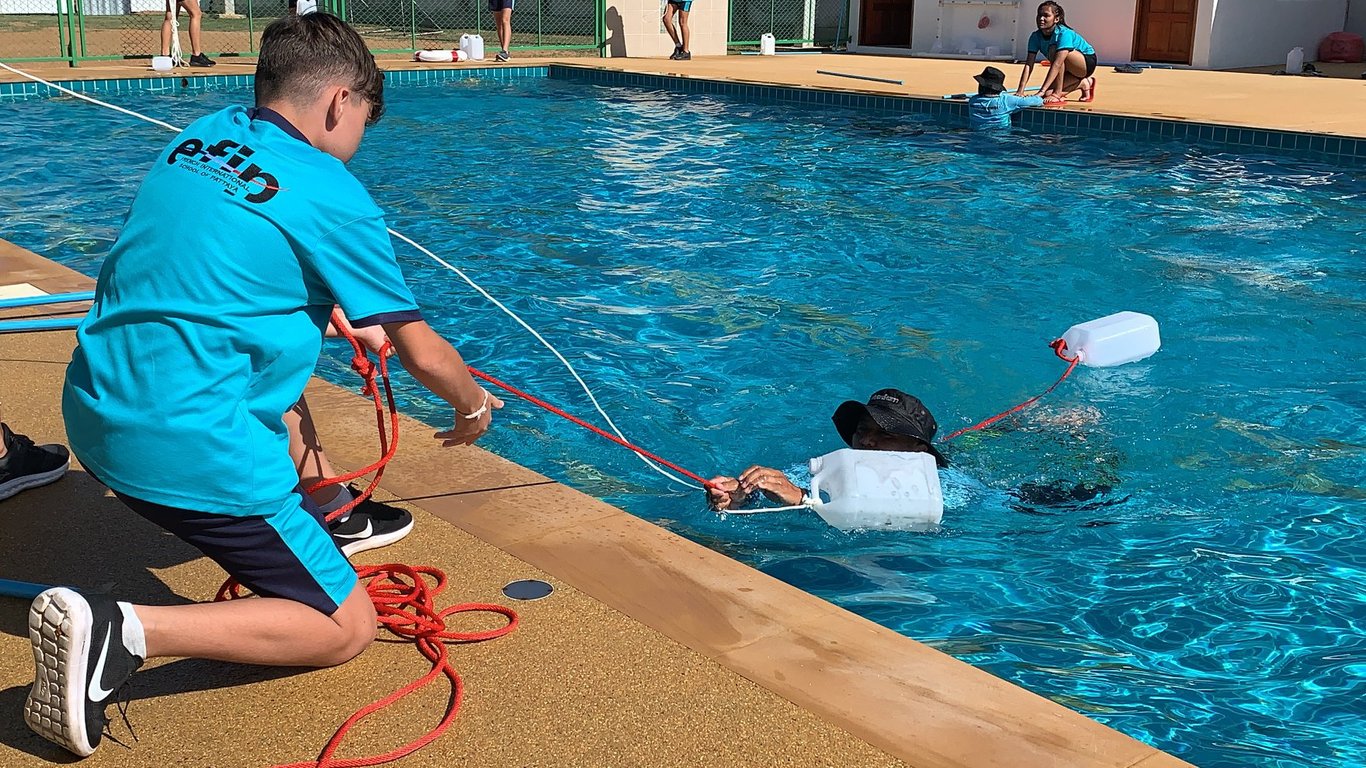 Poolside rescue practice using ropes and floatation devices.