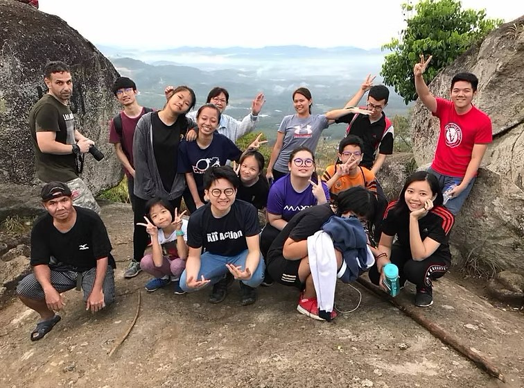 Secondary students pose triumphantly at the peak after a challenging school-organized hike.
