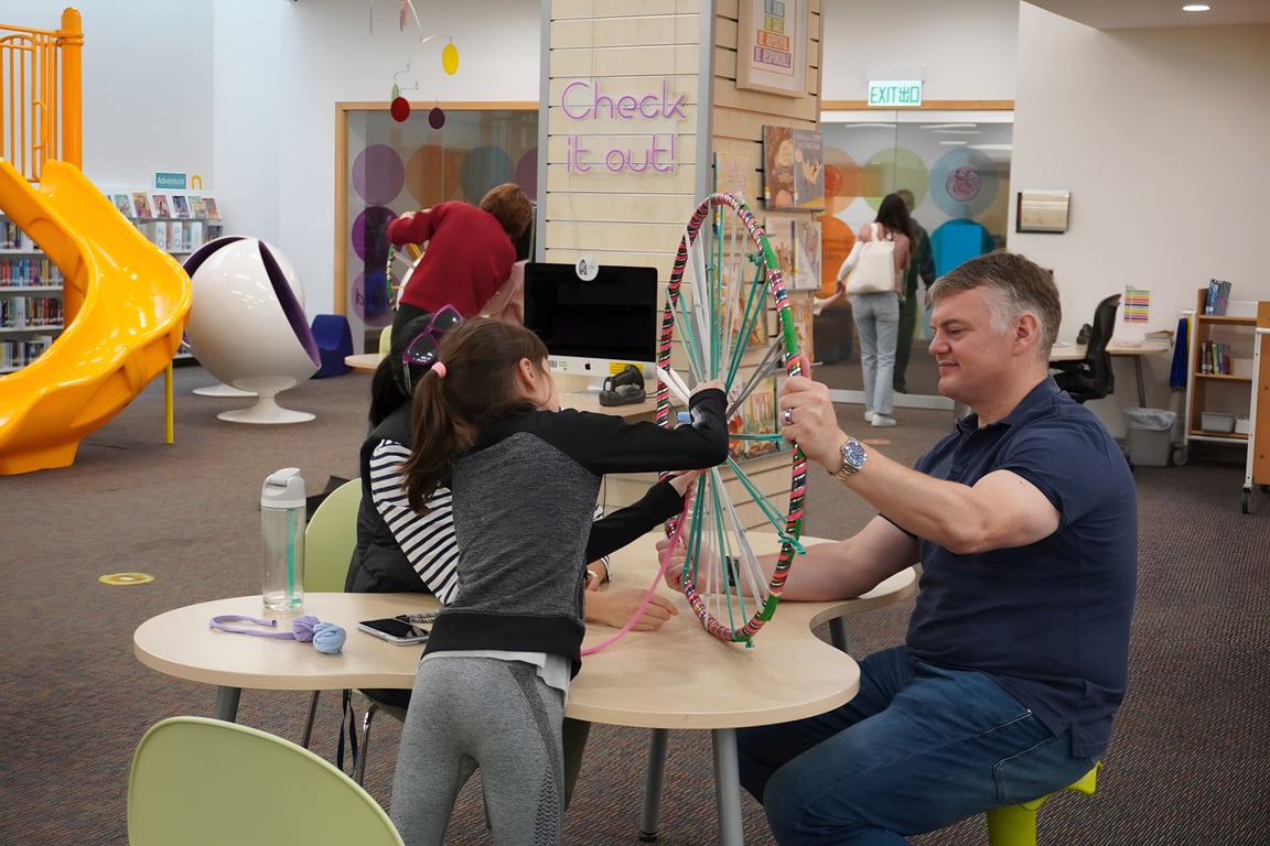 Students and parents engaging in hands-on creativity in the library makerspace.