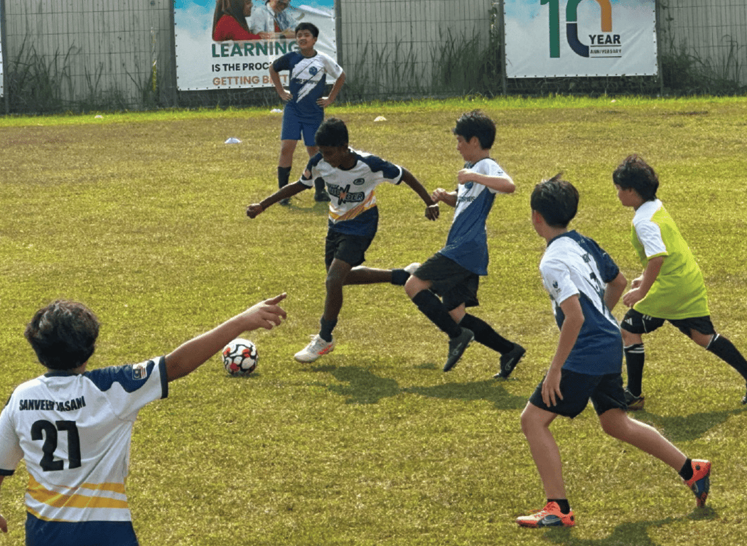 Students playing against another school's football team in a friendly match.