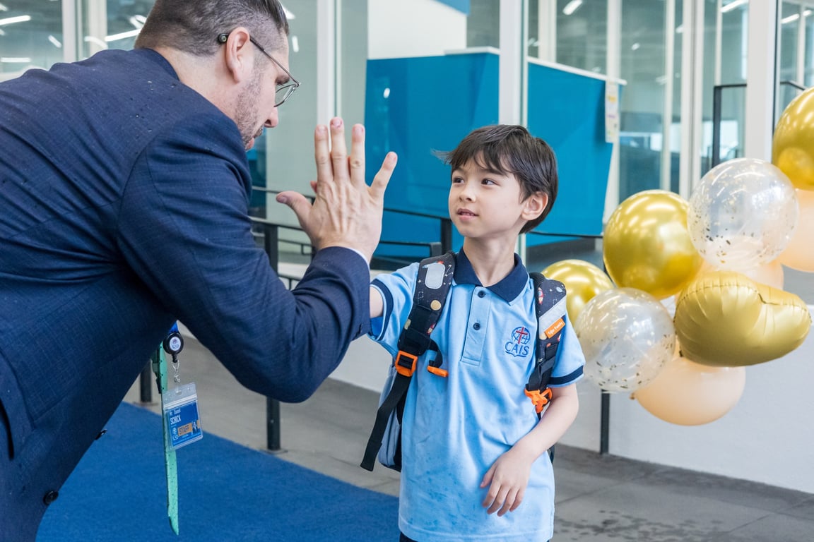 Prep student greeting a teacher with a high-five.
