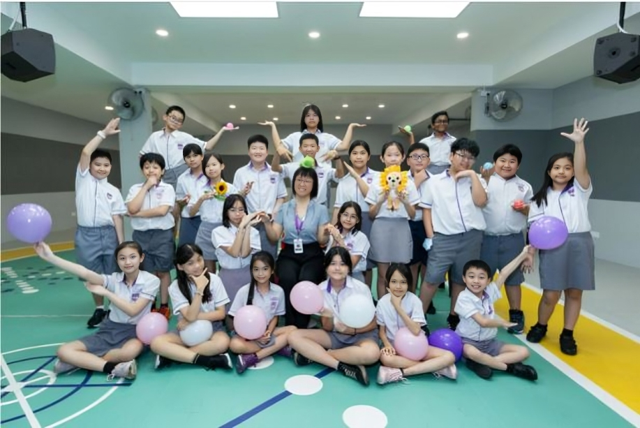 A cheerful group photo from a class celebration filled with balloons and smiles.