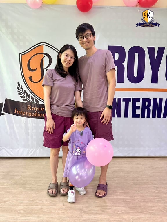Parents posing with their daughter at the annual nursery performance event.