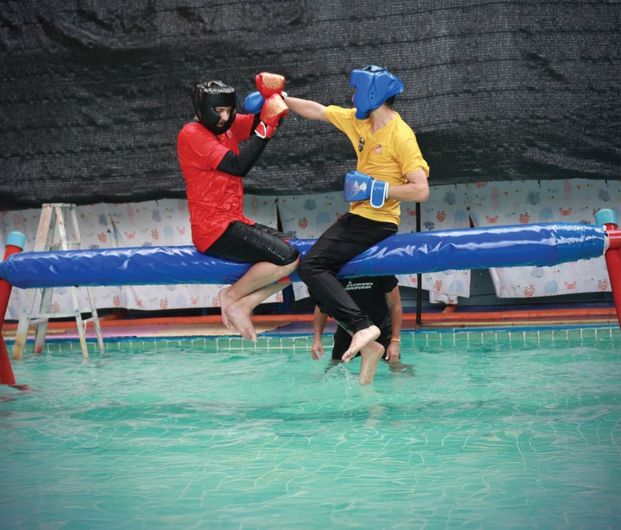 Participants play pool boxing game at community event.