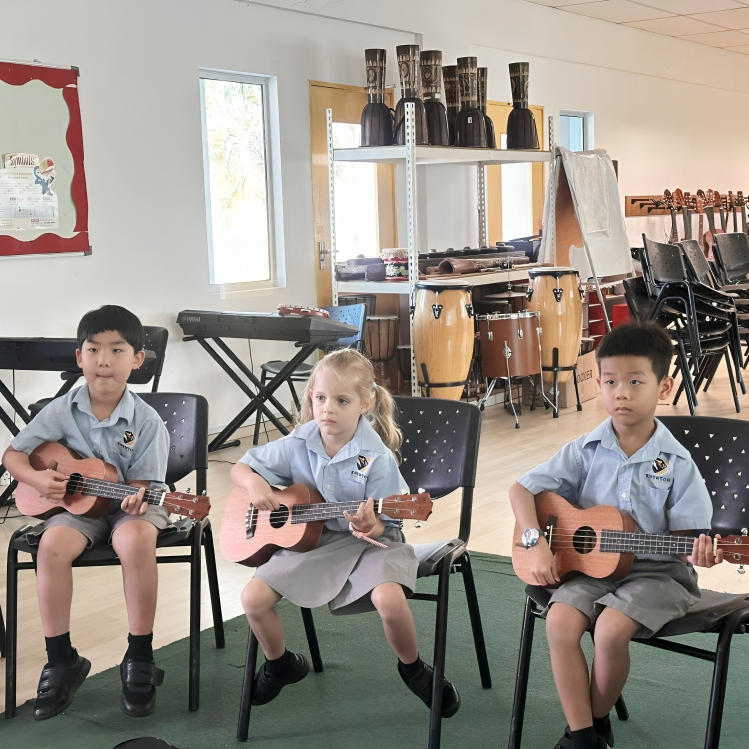 Primary students learn rhythm and chords during ukulele practice in Knewton’s music room.