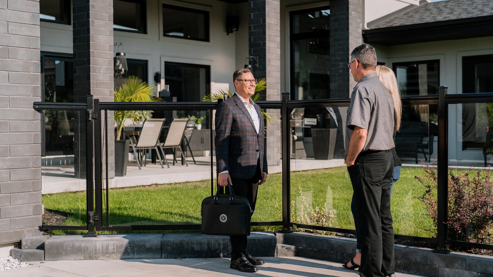 Courtier immobilier rencontrant des acheteurs devant une propriété résidentielle
