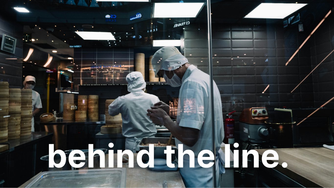 Restaurant cooks operate in a dim-lit kitchen