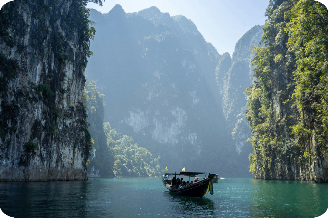 A small boat travelling through cliffs in Thailand.
