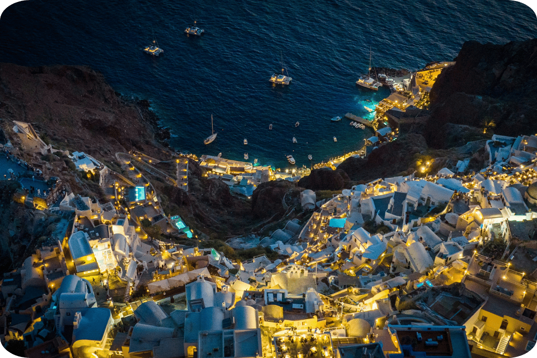 a top down view of santorini at night, lot's of white buildings with warm yellow lights.
