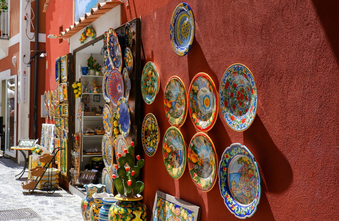 Intricately detailed porcelain plates hung on a red wall outside of a shop.