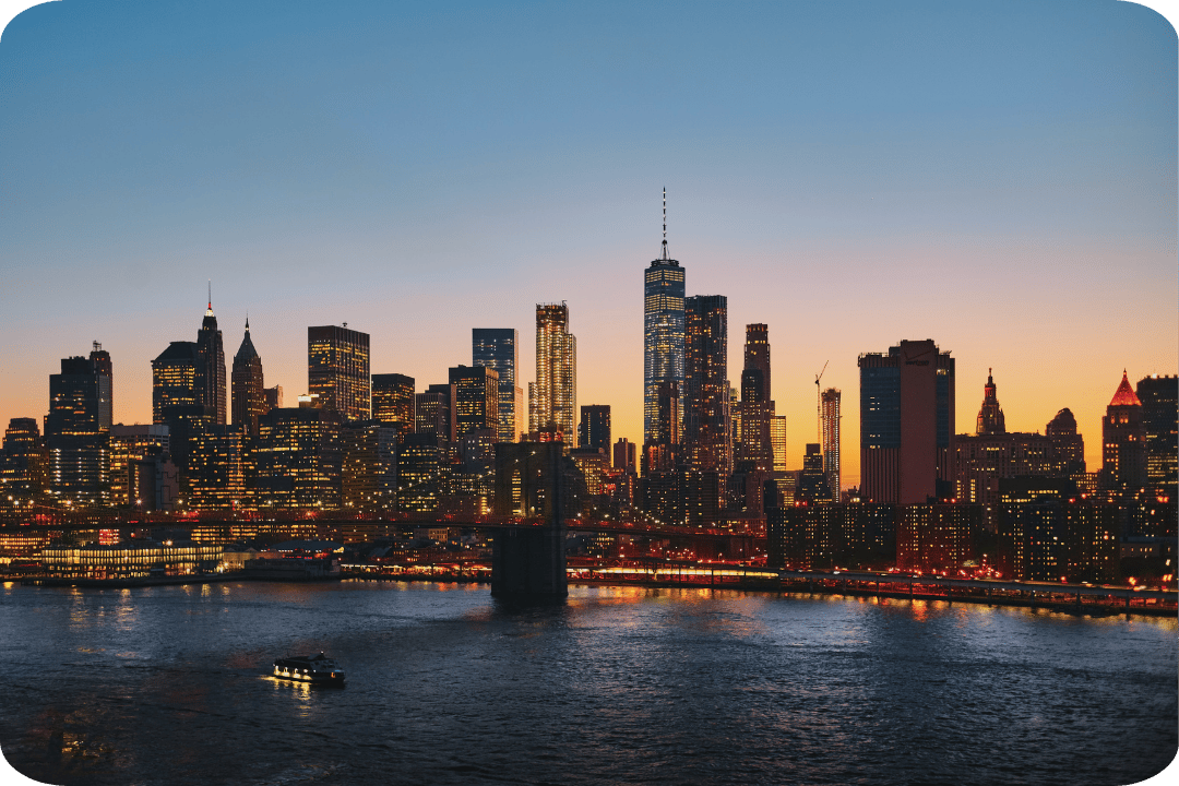 NYC skyline at sunset. High rise buildings with warm lights on.