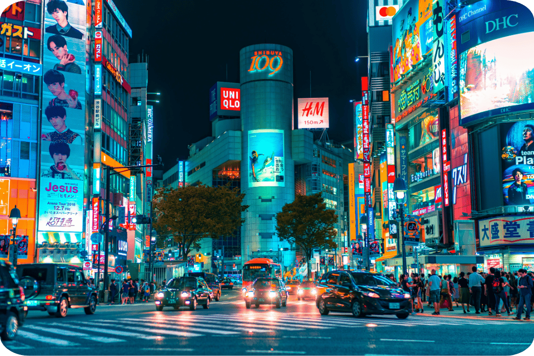 Vibrant city at night. Buildings with advertising screens. Cars driving.