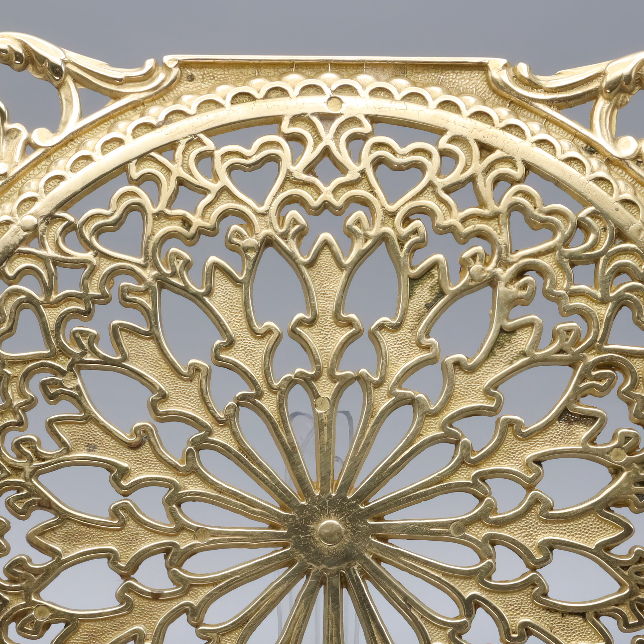 Antique brass trivet detailed view showing ornate vintage metalwork and intricate design pattern