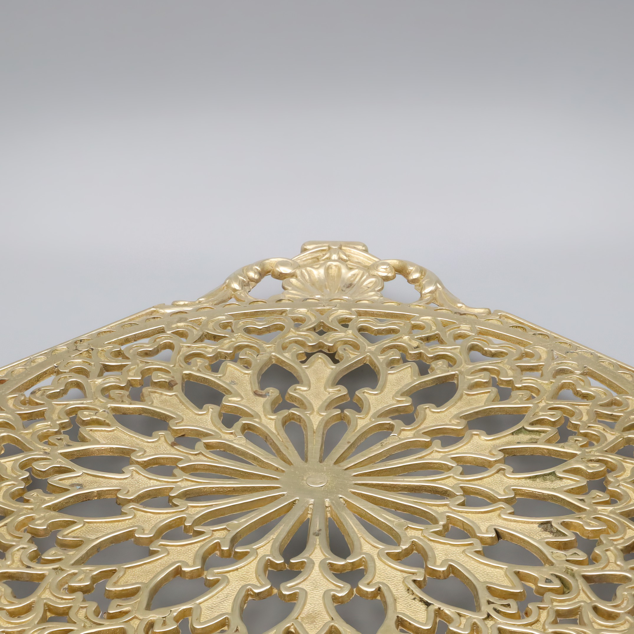 Antique brass trivet detailed view showing ornate floral pattern and intricate craftsmanship