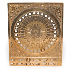 Brass sun perpetual calendar close up showing engraved sundial design and date markers