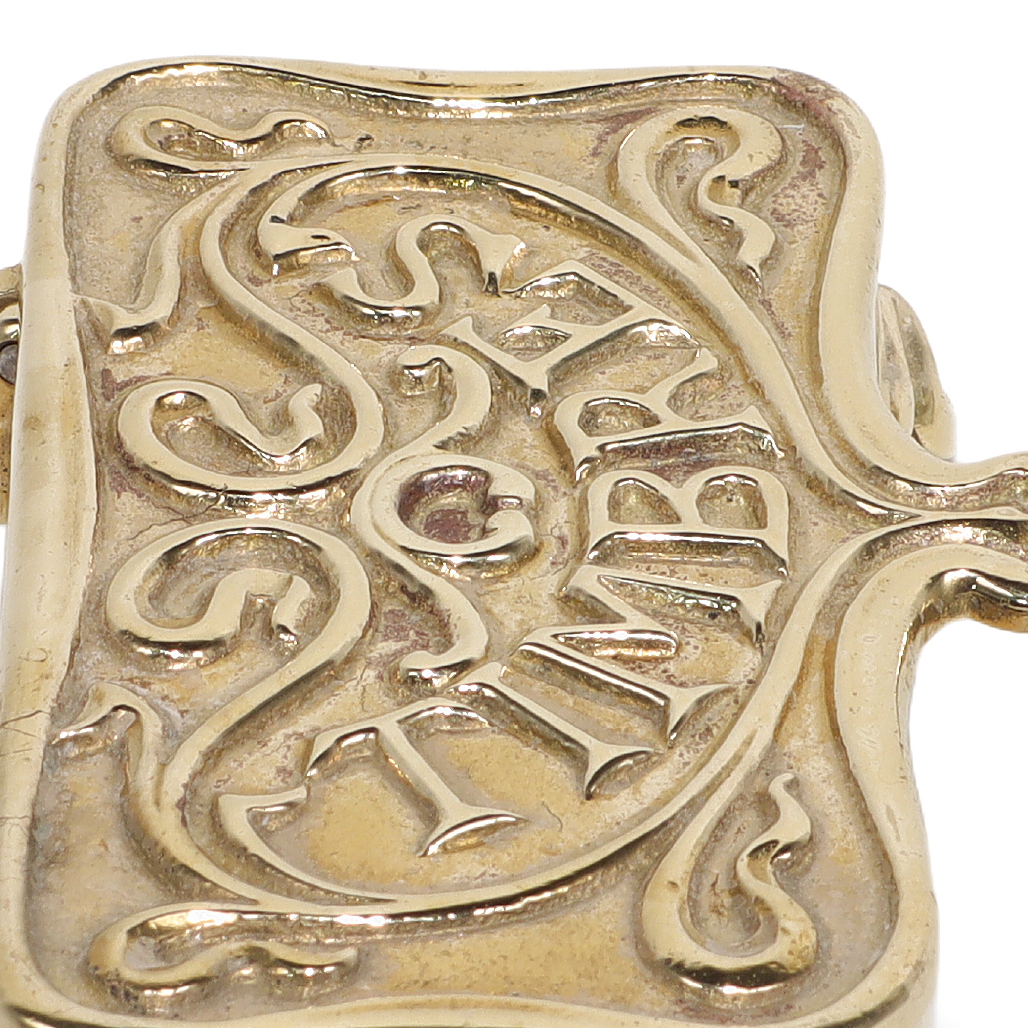 Brass stamp box close up with ornate vintage design and embossed lettering
