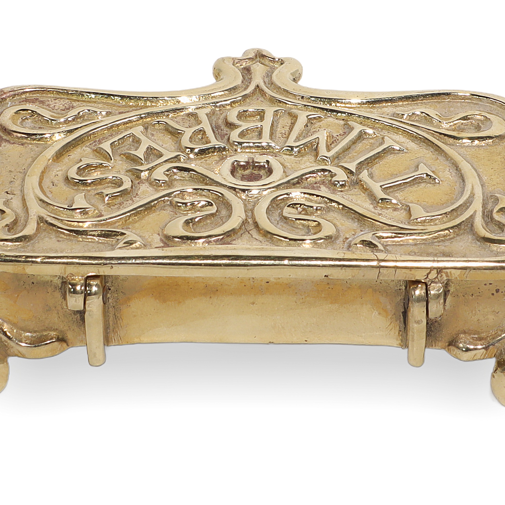 Brass stamp box close up showing ornate vintage design and embossed lettering