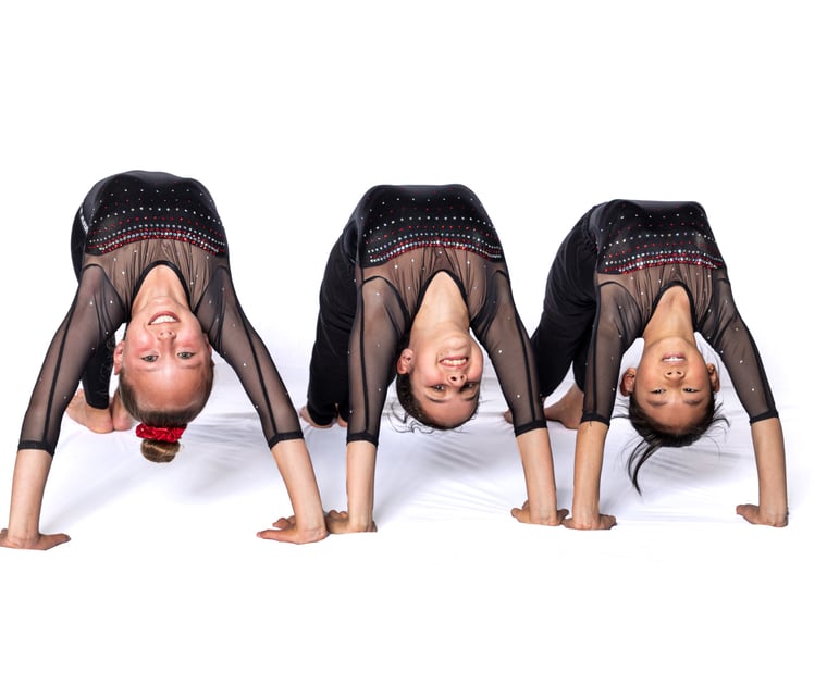 Three gymnasts doing a bridge looking at camera