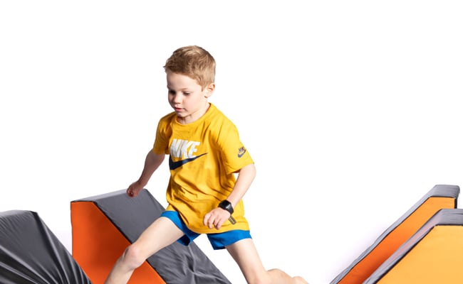 Young boy jumping across for ninja wedge blocks