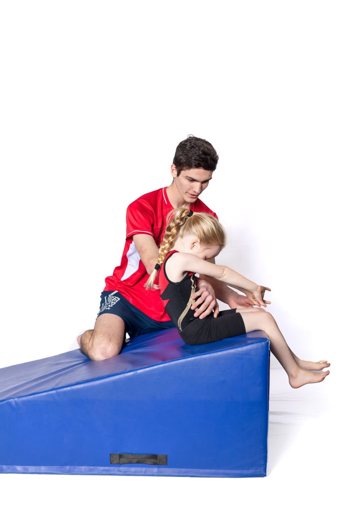 Coach helping a gymnast with a backward roll.