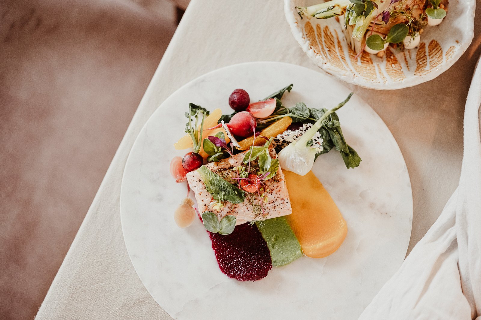 Overhead view of colourful plated wedding dishes featuring seasonal vegetables and edible flowers.