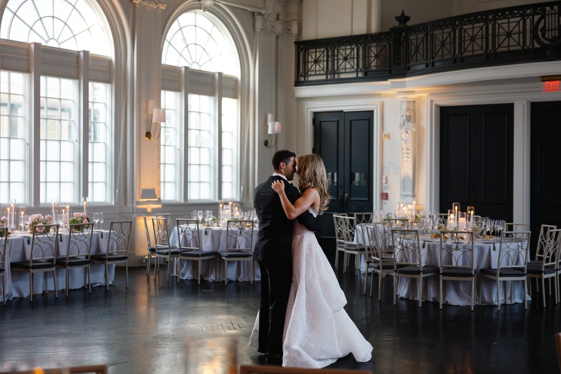 Bride and groom embracing during first dance in grand ballroom