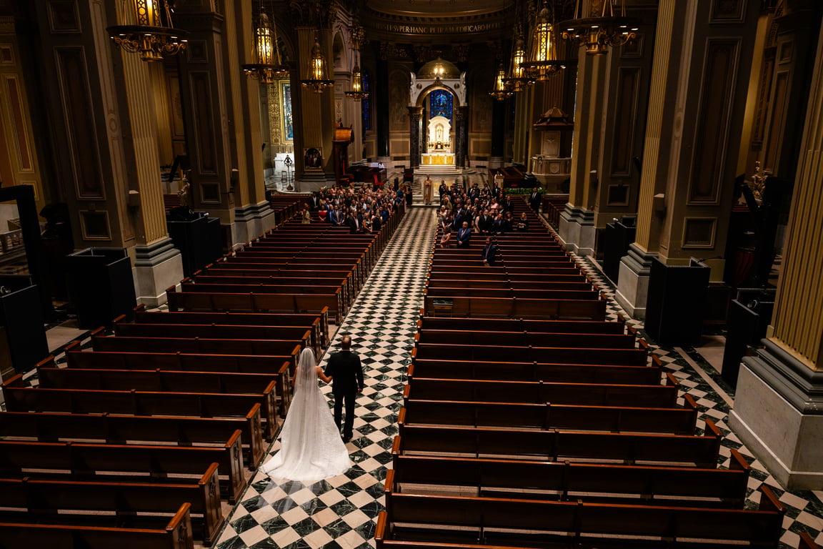 Bride and groom walking down cathedral aisle