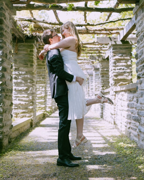 Groom lifting bride under stone pergola
