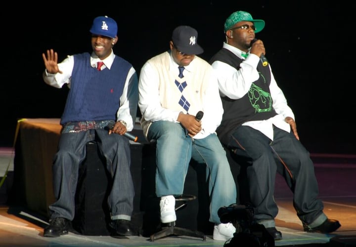 Boyz II Men on stage, sitting, and singing