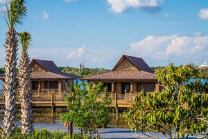 Cinderella's Castle can be spotted in the distance behind two bungalows at Disney's Polynesian Resort