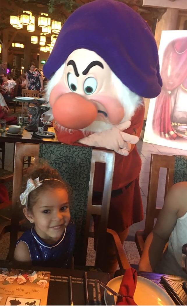 Grumpy Dwarf posing for a photo with a little girl at the Wilderness Lodge Resort.
