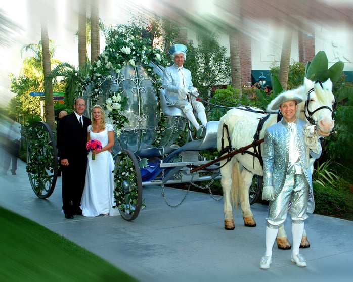Husband and wife standing with Cinderella's carriage.