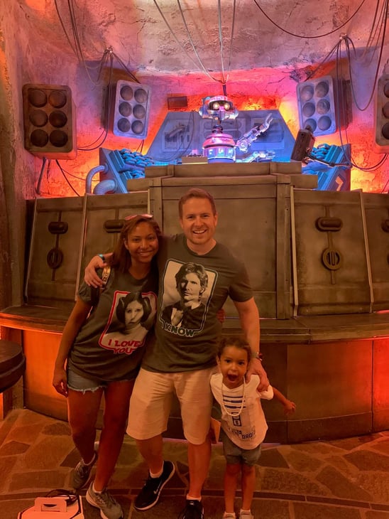 Happy family posing in front of Disney's Galaxy's Edge Star Wars droid.
