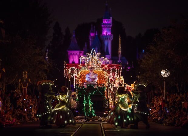 Disneyland electrical parade with castle and pumpkin carriage lit at night