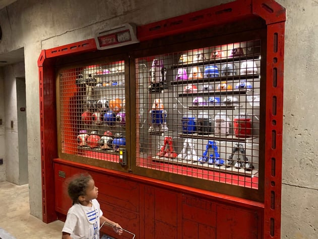 Little girl looking at selection of droid parts at Disney's Galaxy's Edge Star Wars park.