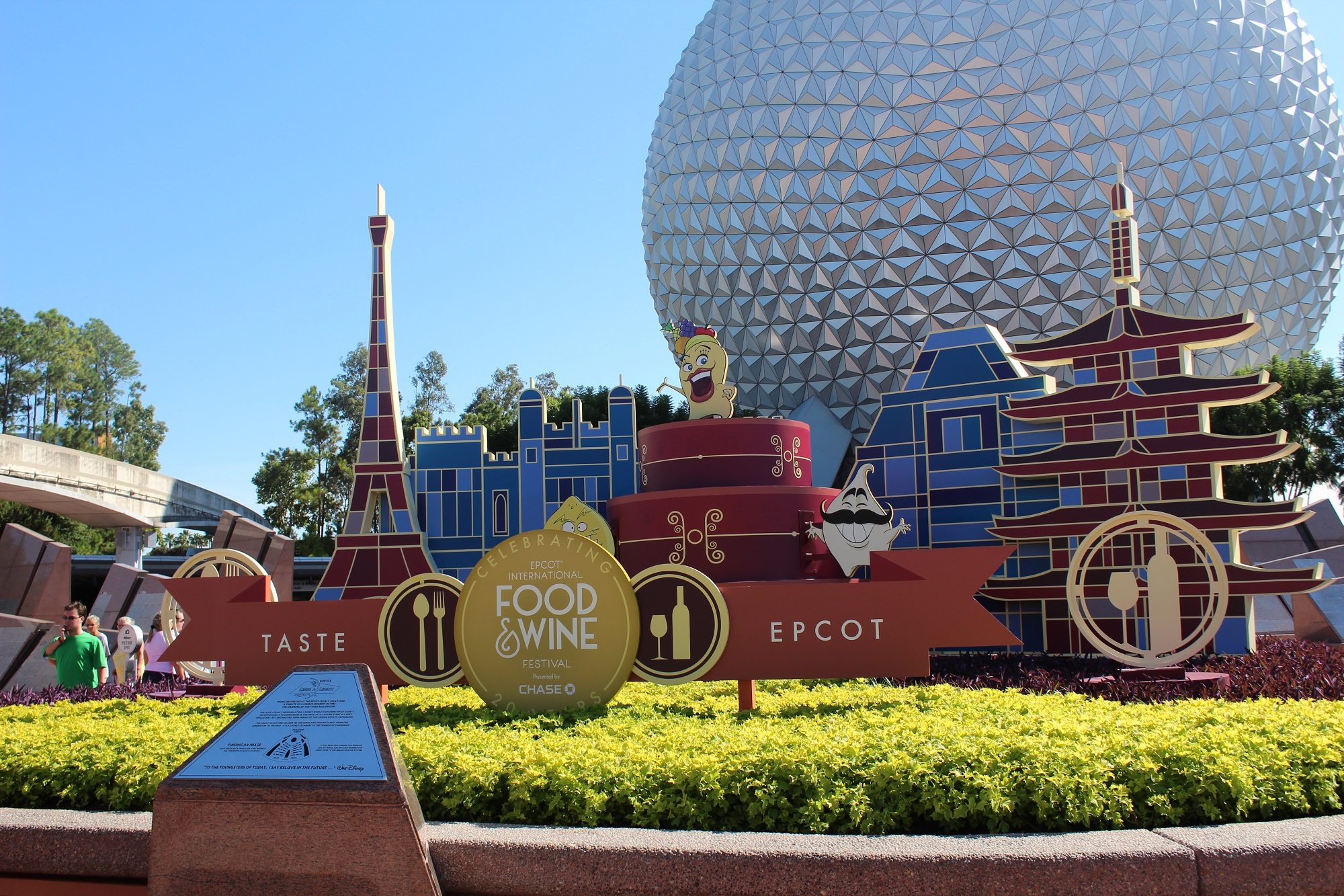 A red and blue sign for Epcot's Food & Wine festival in front of Spaceship Earth's geosphere