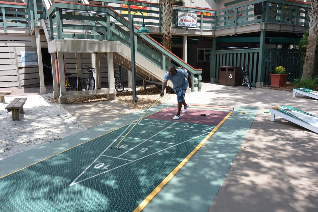 A smiling man plays shuffleboard at Disney's Hilton Head Island Resort