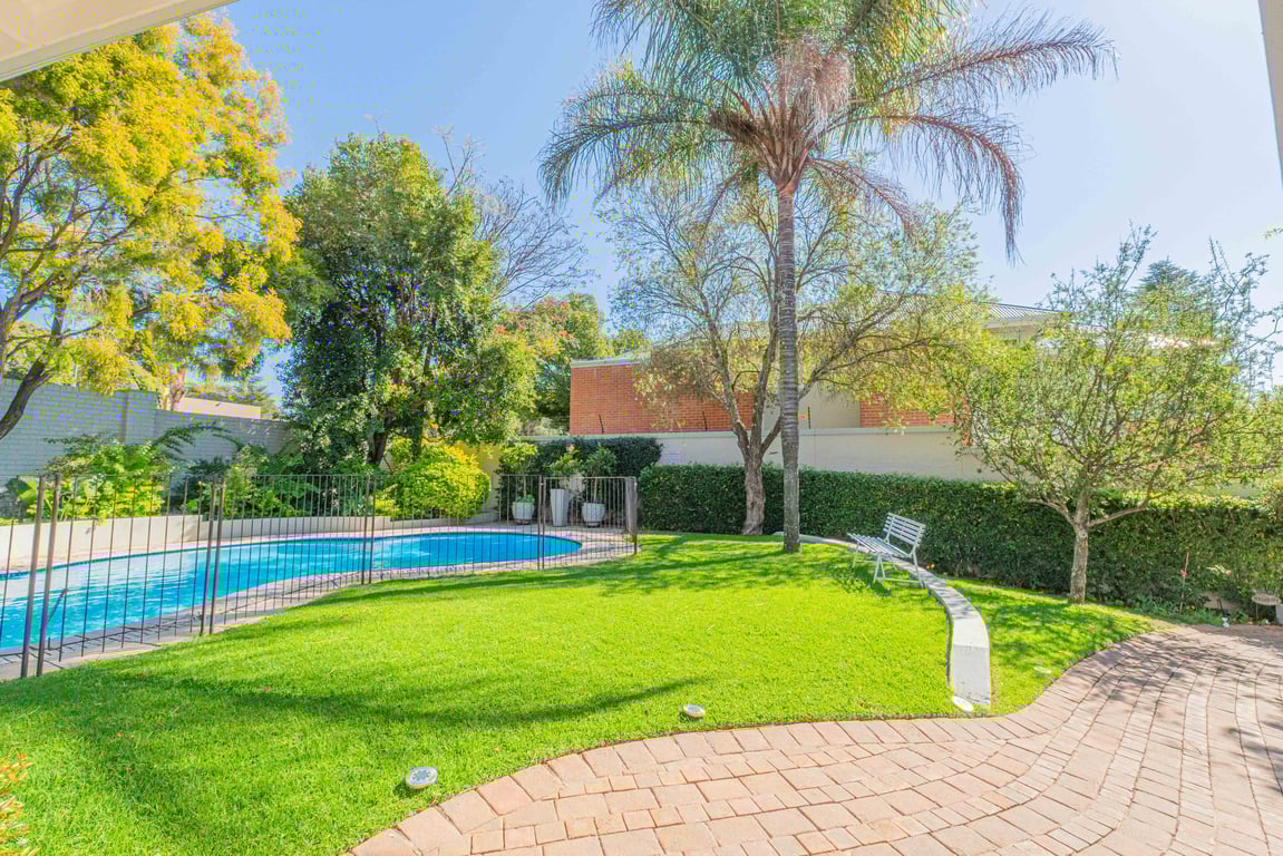 Chaplin Manor garden with pristine pool, manicured lawn, and towering palm trees