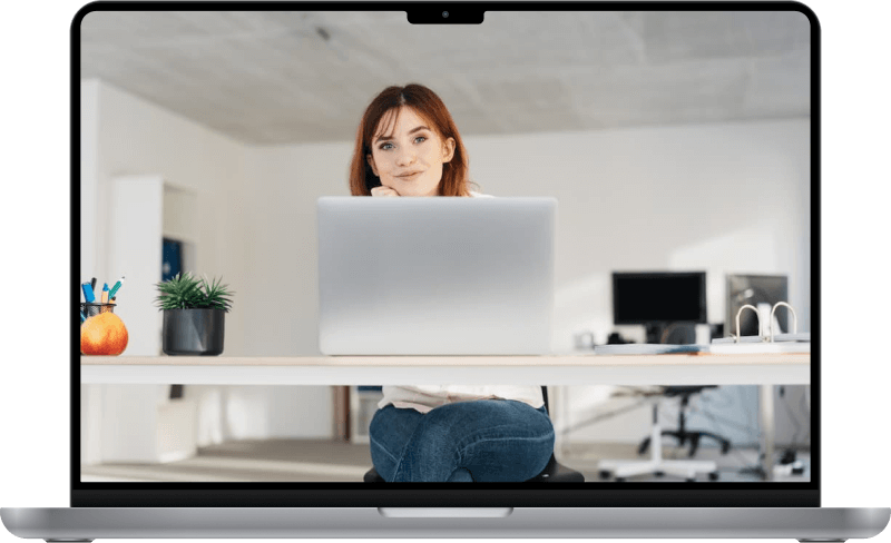 A woman, smiling and looking up from her computer.