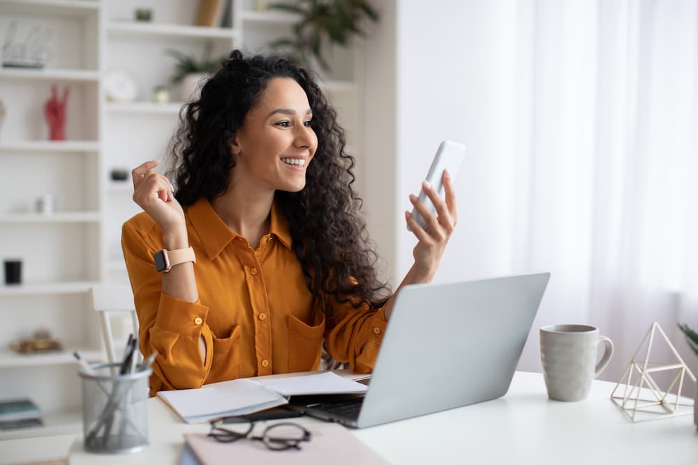 A woman smiling from a text she received from a local business.