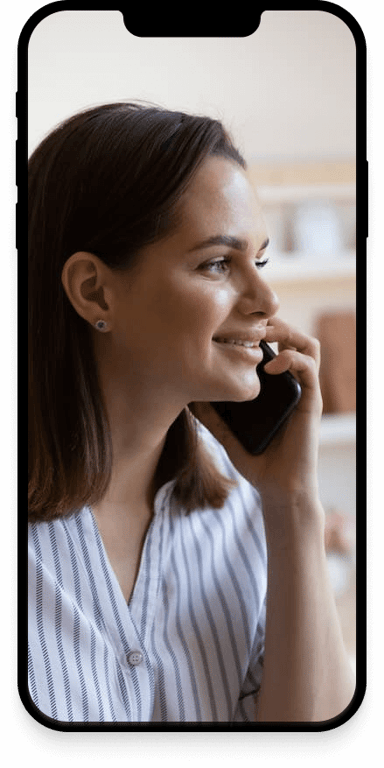 A woman smiling while talking to someone over the phone.