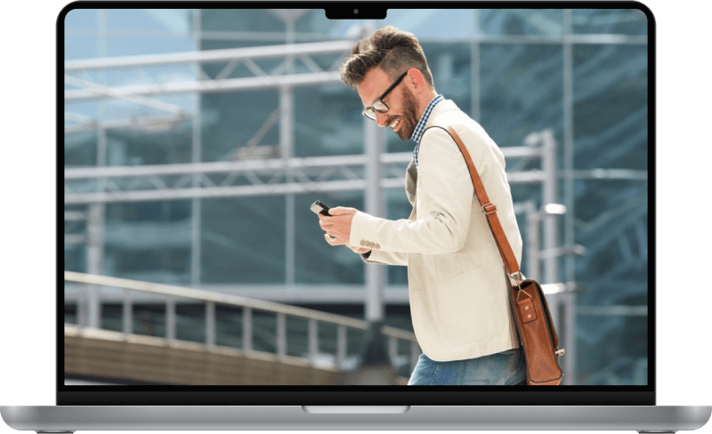 A business man walking and smiling at his phone.